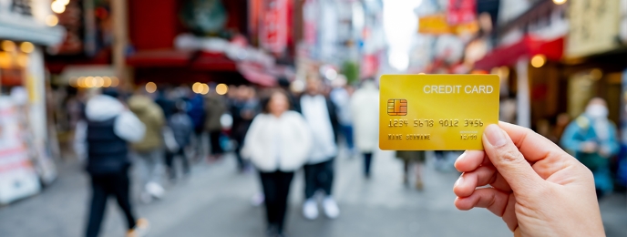 Personal holding IndusInd Bank Forex Card on a busy foreign street highlighting travel ease and money management.